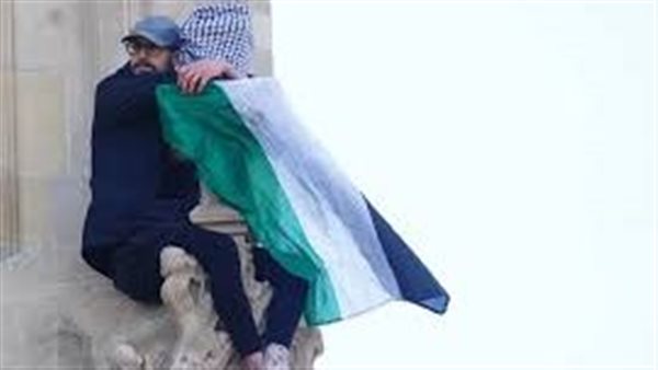 رجل يتسلق بيغ بن حاملًا علم فلسطين