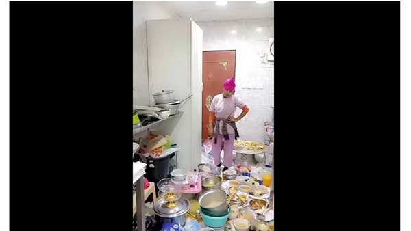 عاملة توثق المطبخ مكتظ بالأواني المتراكمة